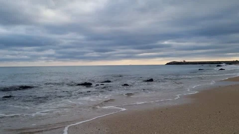 Calm sea under dramatic cloudy sky with gentle waves on shore Stock Footage 322124754