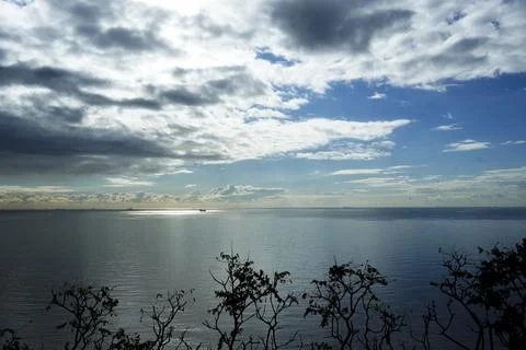 Calm Sea Under Dramatic Cloudy Sky with Distant Ships Foto stock