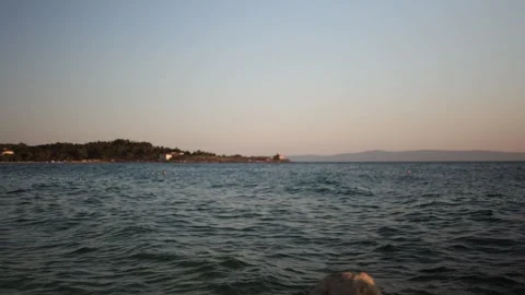 Calm sea waves and distant coastline create a peaceful summer sunset scene Stock Footage 341556757