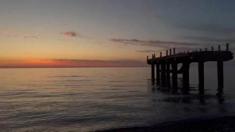 Calm sea waves and old pier at sunset on tranquil evening seascape Stock Footage 319818694