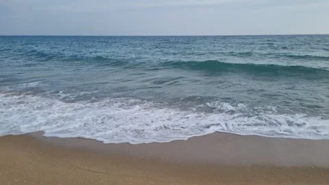 Calm sea waves gently rolling onto the sandy shoreline at sunrise Stock Footage 321651141