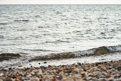 Calm sea waves gently rolling onto a pebble beach on a peaceful day Stock Photos