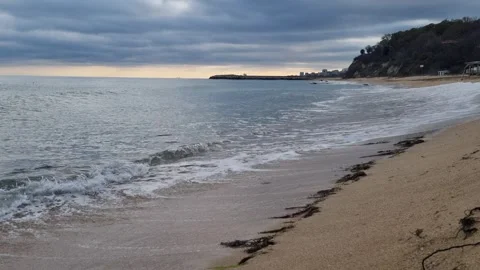 Calm sea waves hitting sandy beach under cloudy dramatic evening sky Stock Footage 322124832