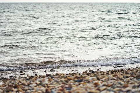 Calm sea waves rolling gently onto a pebble beach with clear water Stock Photos