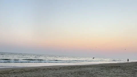 Calm Sea Waves Rolling Onto Sandy Beach Under a Soft Pastel Sky Video stock 343335012