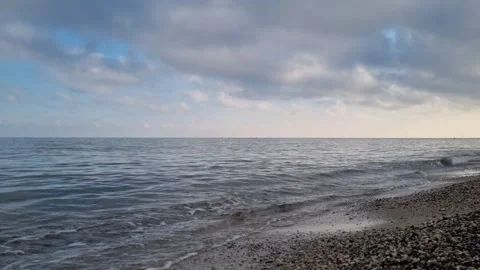 Calm sea waves under cloudy evening sky on peaceful coastline Stock Footage 322093108