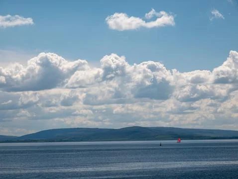 Calm seascape with dramatic clouds and distant sailboat Foto stock