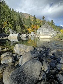 Calm section of river surrounded by boulders. Stock Photos