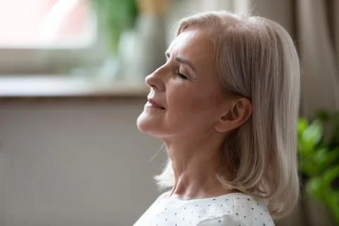 Calm serene middle aged woman breathing with eyes closed Stock Photos