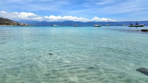 Calm, Shallow Waters with Distant Boats and Hills under a Clear Blue Sky Stock Footage 283987907