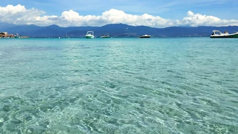Calm, Shallow Waters with Distant Boats and Hills under a Clear Blue Sky Stock Footage 283987987
