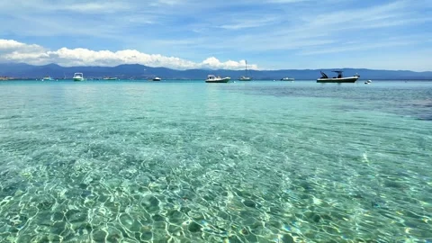 Calm, Shallow Waters with Distant Boats and Hills under a Clear Blue Sky Stock Footage 283988029