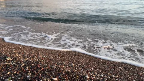 Calm shoreline with gentle waves rolling over colorful pebbles Stock Footage 297513298
