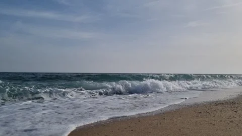 Calm shoreline with soft waves under light cloudy blue daytime sky Stock Footage 322124556