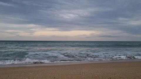 Calm shoreline with soft waves under light cloudy blue daytime sky Stock Footage 322124590