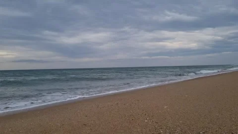 Calm shoreline with soft waves under light cloudy blue daytime sky Stock Footage 322124591