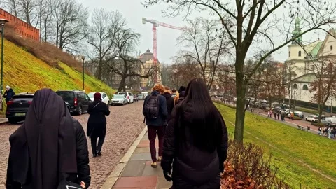 A calm, slow-motion perspective of people walking down a cobblestone path near Video stock 333693956