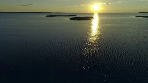 Calm sunset landscape water surface shining sun sky horizon islands aerial drone Stock Footage