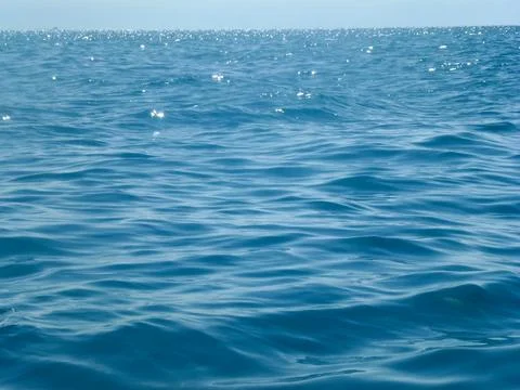 The calm surface of the sea waves under the bright sun. Summer seascape Stock Photos