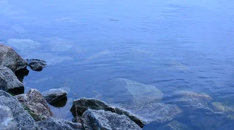 Calm transparent blue water surface with rocks Stock Footage 50845860