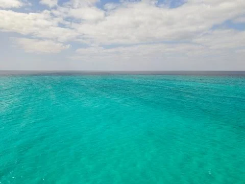 Calm turquoise ocean under cloudy sky Stock Photos