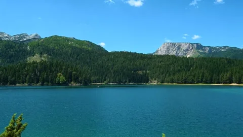 Calm turquoise waters reflect sky and mountains. Black Lake, Montenegro Stockbeeldmateriaal 342969164
