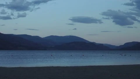 Calm View of Sandy Beach Mountains in Background with Some Clouds in Sky Stock Footage 232050295