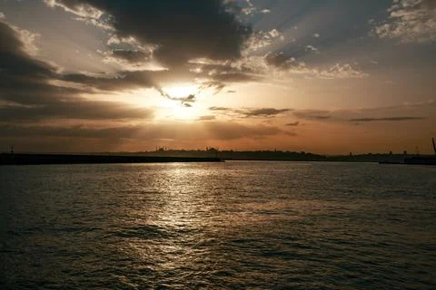 Calm view of the sunset gliding through the clouds over the calm sea Foto stock