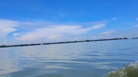 Calm water with gentle waves under blue sky with white clouds Vídeo Stock 331806217