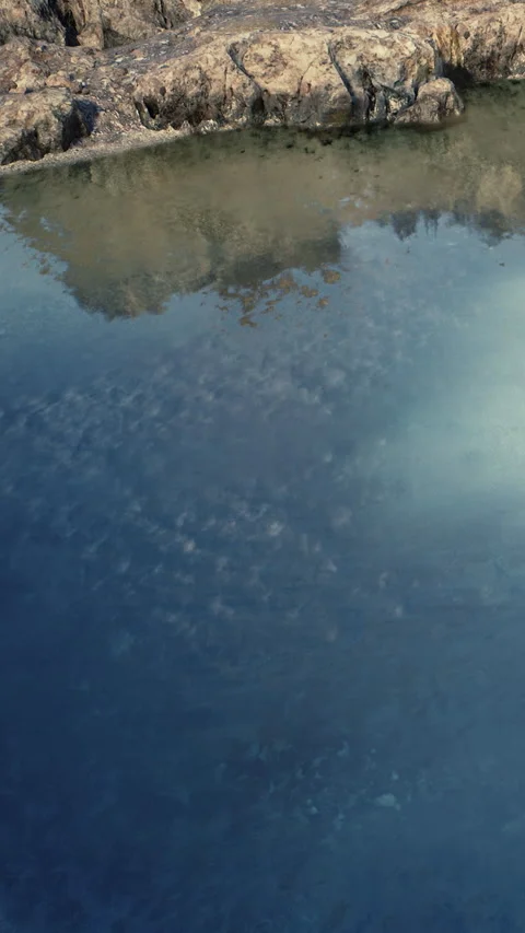 Calm water reflecting mountains during bright day in outdoor setting Stock Footage 339102459