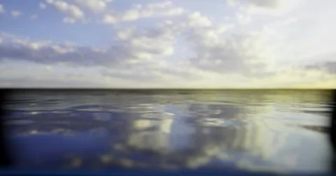 Calm water reflects soft clouds at sunset over the horizon Stock Illustration