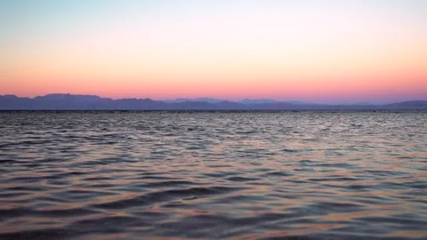 Calm water surface and mountain range on the opposite shore of the lake at Vidéo 253209473
