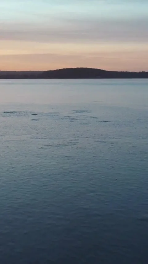 Calm water surface of lake at sunset with hills Stock Footage 334169473