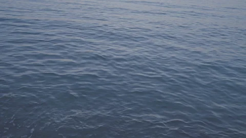 Calm water surface with small waves illuminated by sunset Video stock 251826415