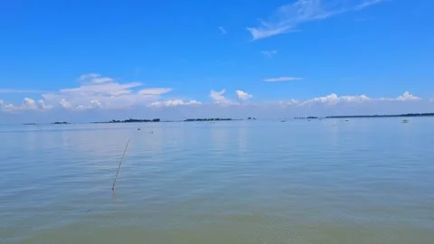 Calm water under blue sky with clouds and land in distance Vídeo Stock 331806249