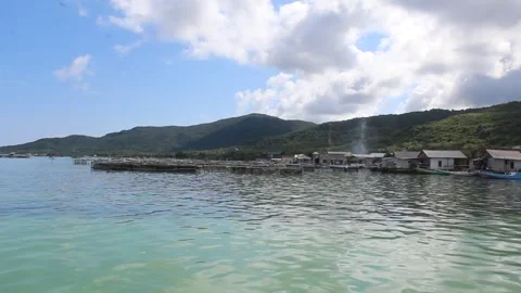 Calm water wave of Java Sea, with green hill and traditional wooden building Stock Footage 294854737