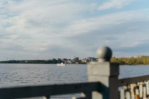 A calm waterfront scene featuring a lakeside railing in the foreground, with Stock Photos