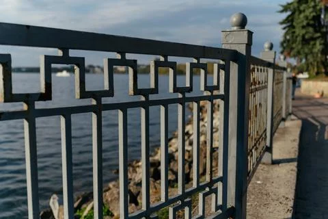 A calm waterfront scene featuring a lakeside railing in the foreground, with Stock Photos