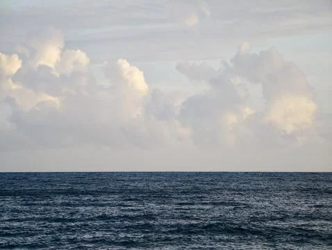 Calm waters beneath soft cloud formations, Gentle ocean scene under muted s.. Stockfoto's