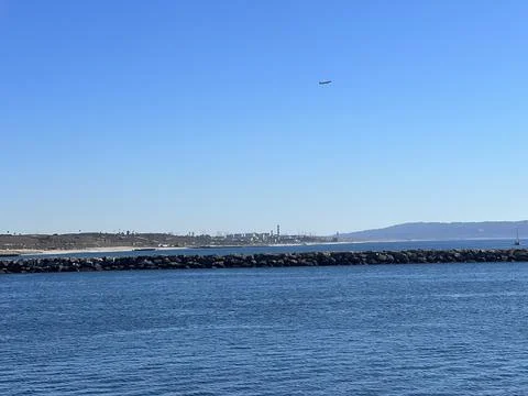 Calm Waters Mirror the Clear Sky as Planes Soar Above a Quiet Coastal Landscape Stock Photos