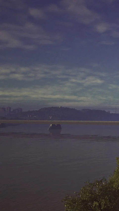 Calm waters reflect distant city skyline under a dreamy sky Stock Footage 331692224