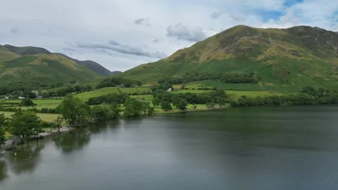 Calm waters reflect rolling green hills under a soft sky Stock Footage 345524824