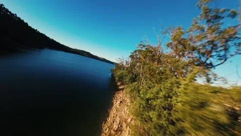 Calm waters reflect sky as camera glides over forested shores Stock Footage 342270851