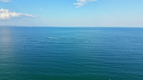 Calm waters stretch across a vast ocean under a blue sky with soft clouds in the Stock Footage 340856354