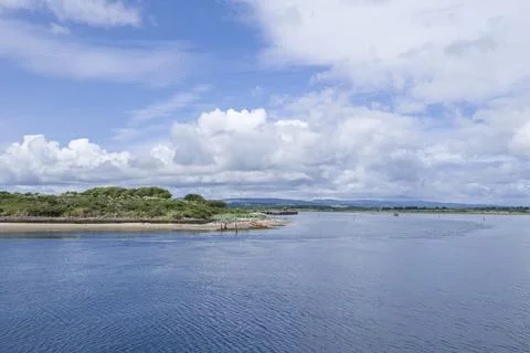 Calm waters stretch under a bright, partly cloudy sky Stock-Fotos
