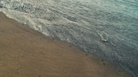 Calm Wave on Black Sand Beach Leaving Wet Sand Slowly Drying Texture Stock Footage 334559580