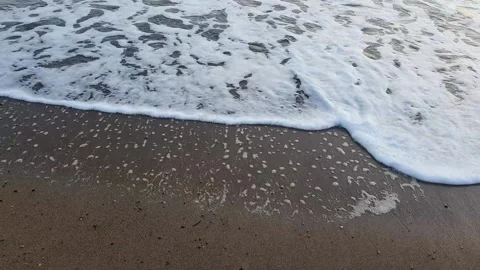 Calm wave foaming at the coast touching the blond sand Stock Footage 148242261