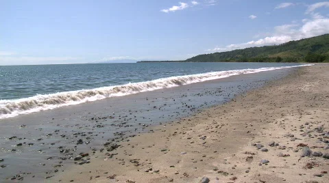 Calm wave rolling onto sandy beach with dark pebbles Video stock 605991