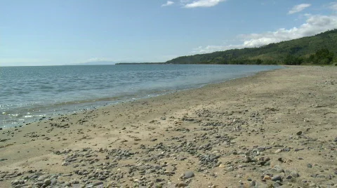 Calm wave rolling onto sandy beach with dark pebbles Video stock 606062