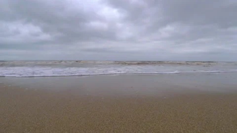 Calm waves coming towards the camera view in a lonely beach during a cloudy day Stock Footage 133736116